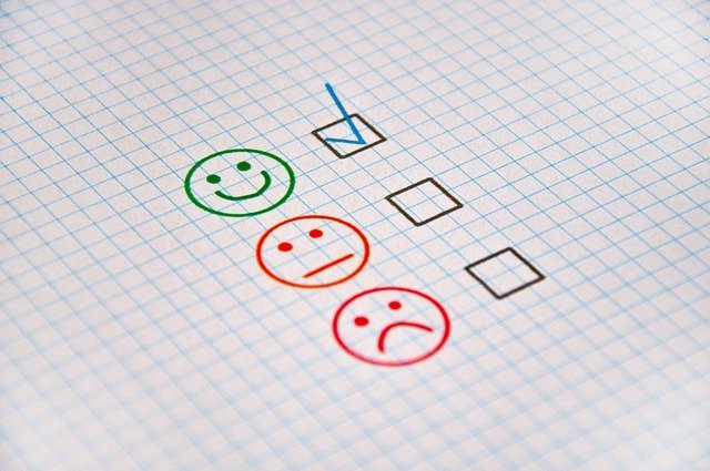 An image of three faces drawn on a piece of paper: happy, neutral and sad. A checkmark is placed next to the happy face.